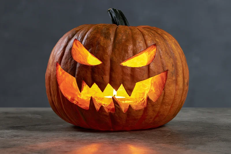 Carved pumpkin with glowing angry face on a dark surface