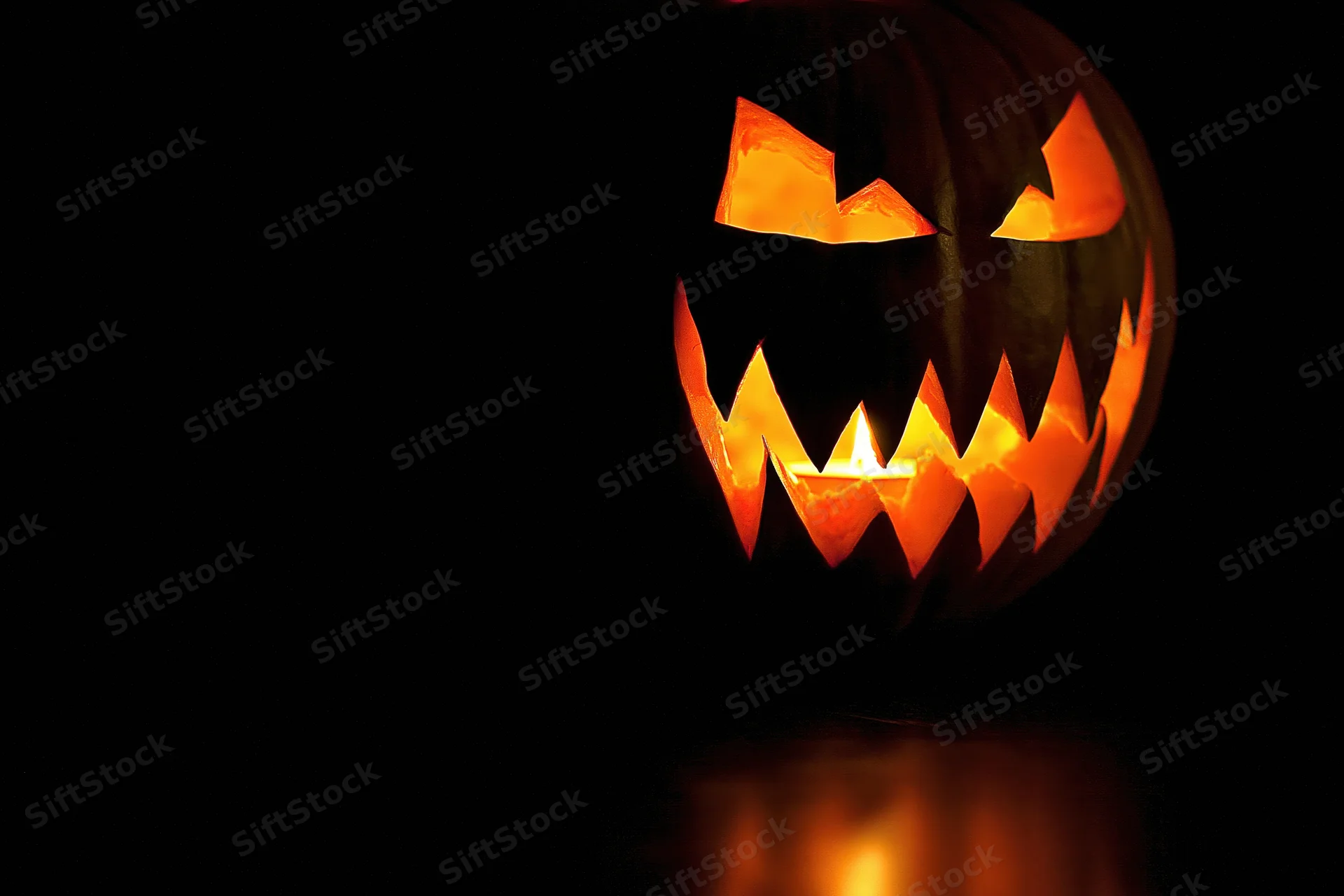 Carved jack-o-lantern with jagged grin glowing in the dark