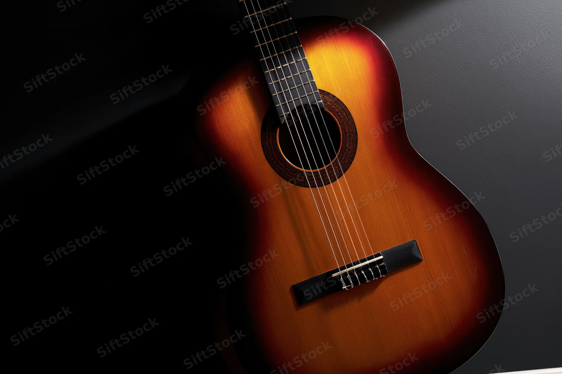 Classical acoustic guitar resting upright against dark background with spotlight highlighting its sunburst wood finish