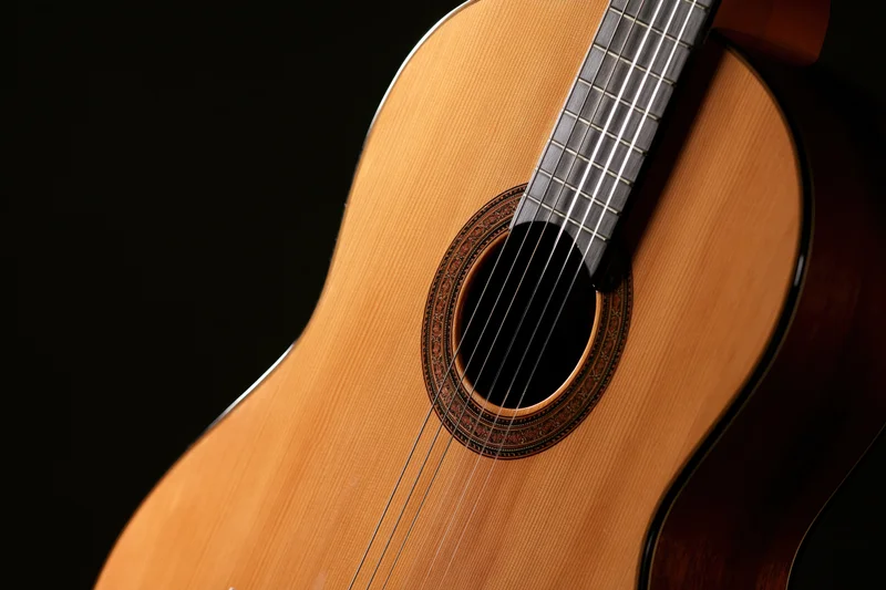 Close-up of a classical acoustic guitar showing wood grain and soundhole against black background
