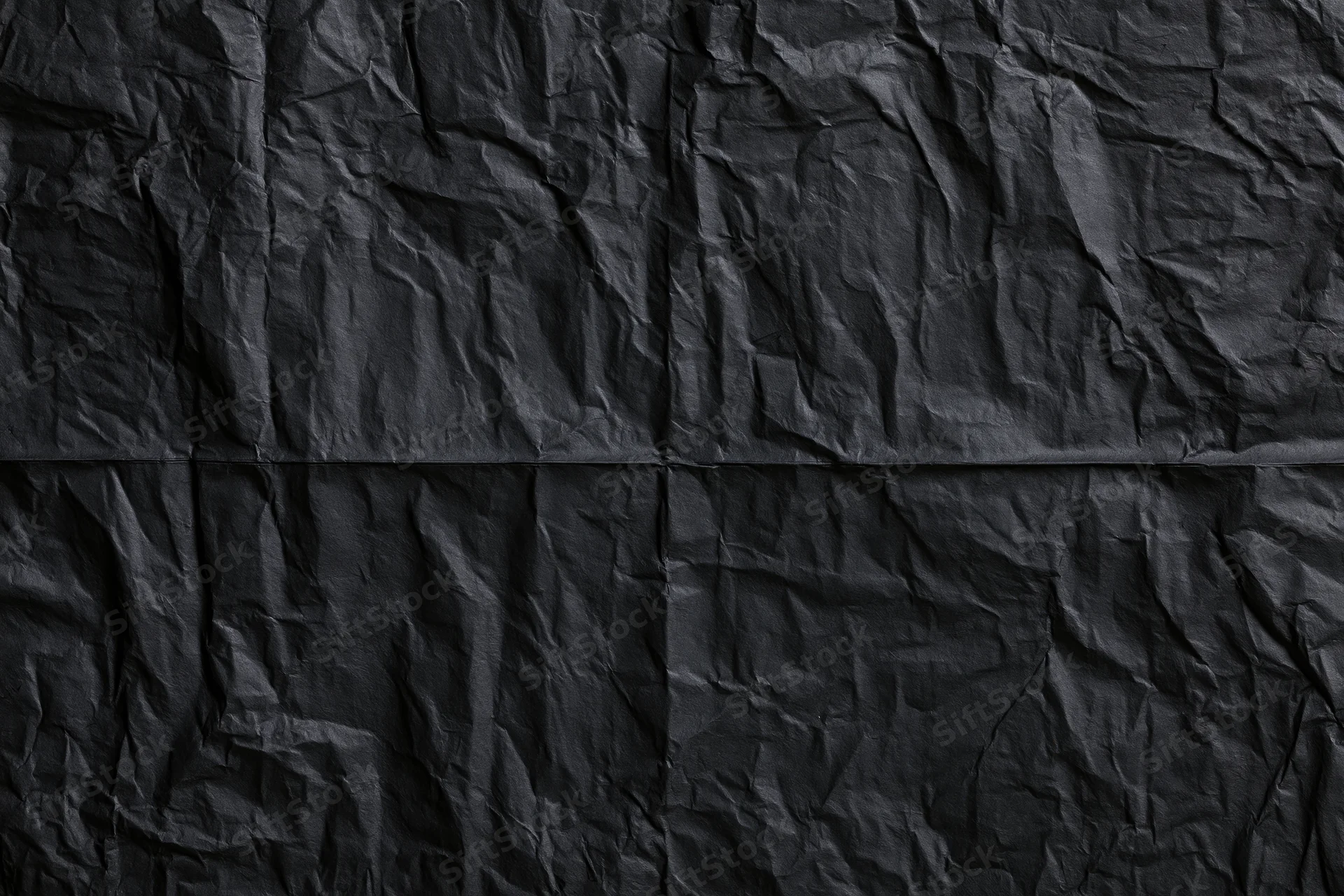 Crumpled black wheat-paste poster paper in flat lay closeup
