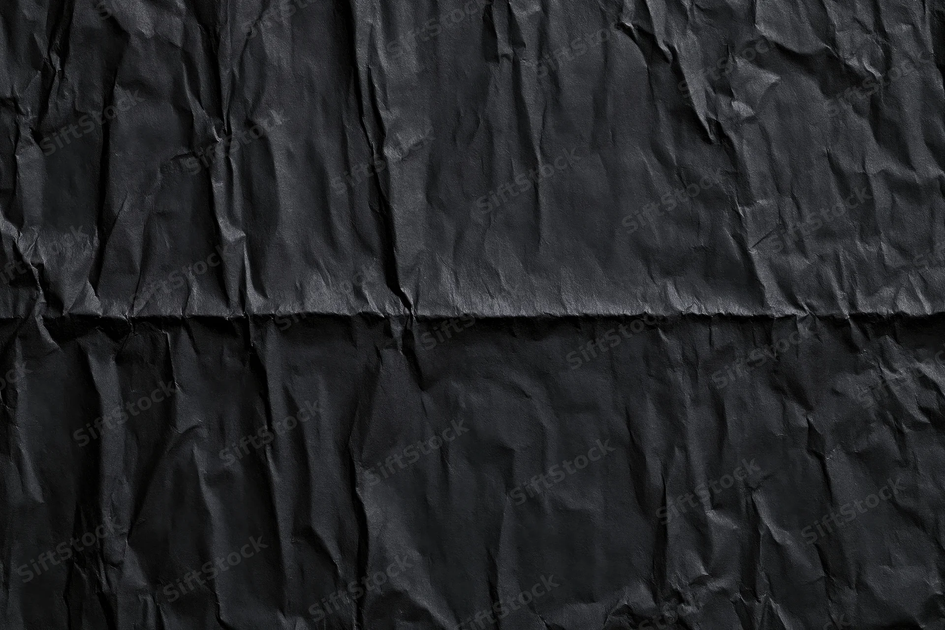 Crumpled black paper texture with creases and folds filling the frame