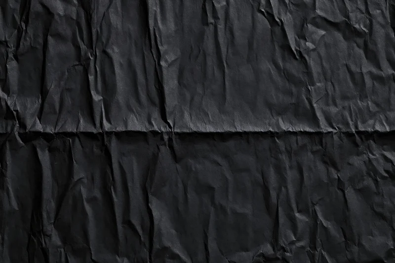 Crumpled black paper texture with creases and folds filling the frame
