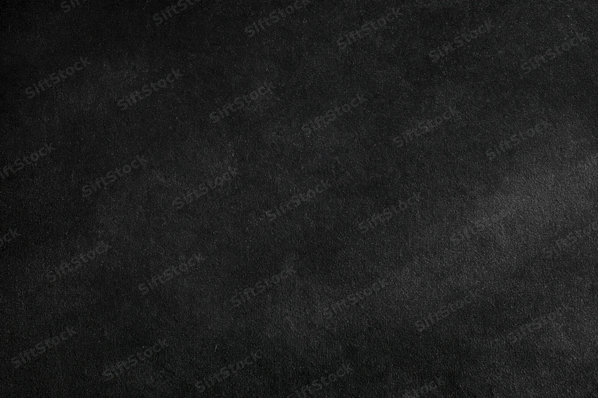 Close-up of a dark black velvet surface with subtle texture and gradient lighting