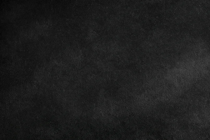 Close-up of a dark black velvet surface with subtle texture and gradient lighting