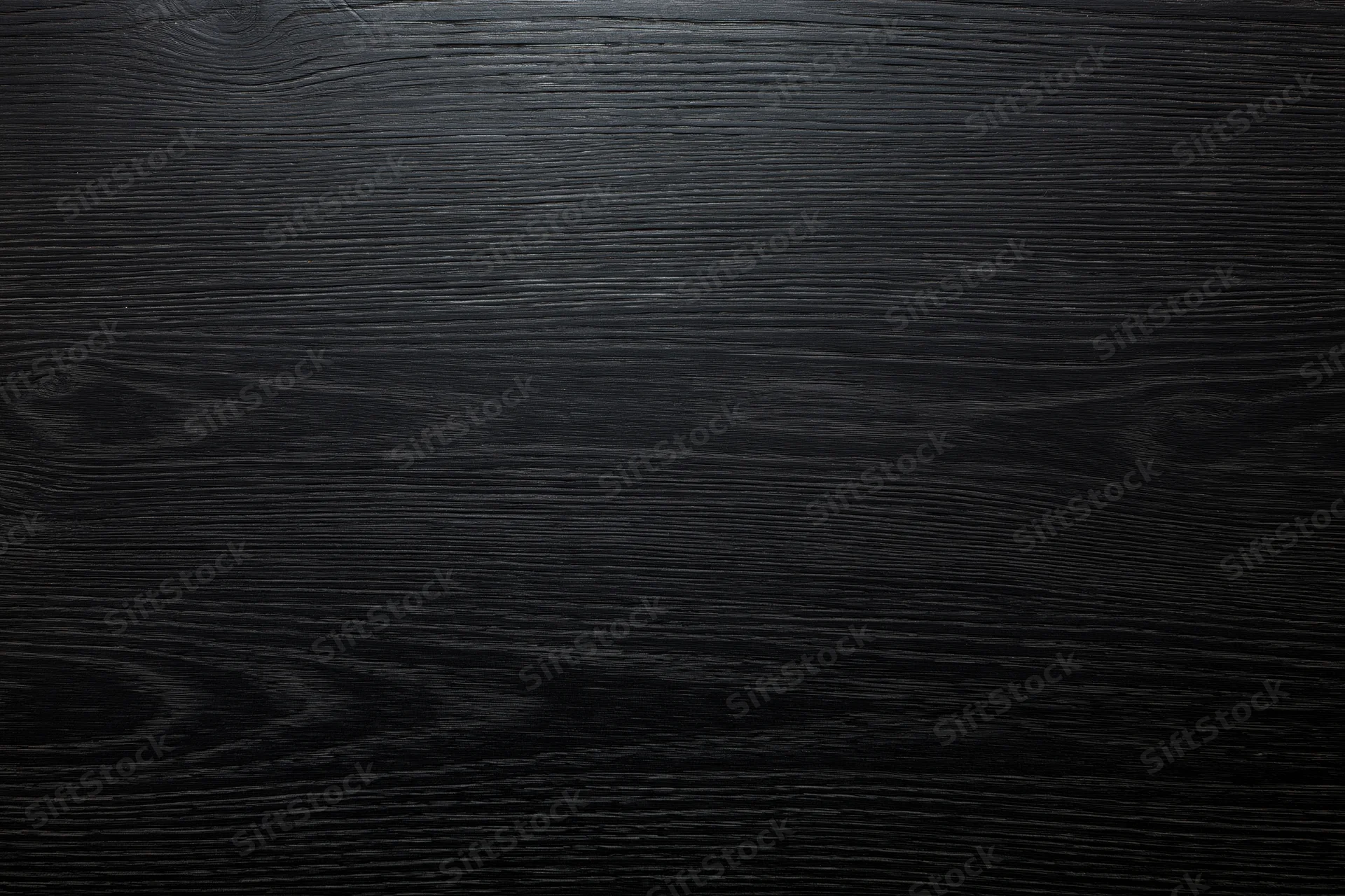Close-up of dark ebony wood surface with visible grain pattern filling the frame