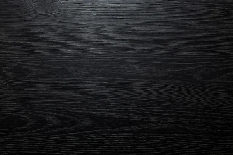 Close-up of dark ebony wood surface with visible grain pattern filling the frame