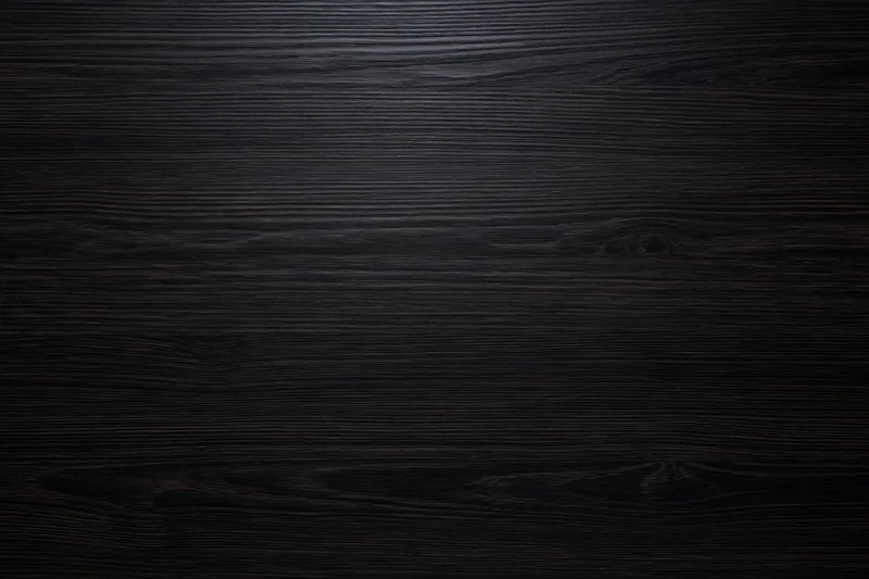 Close-up of dark ebony wood surface with visible grain and knots filling the frame
