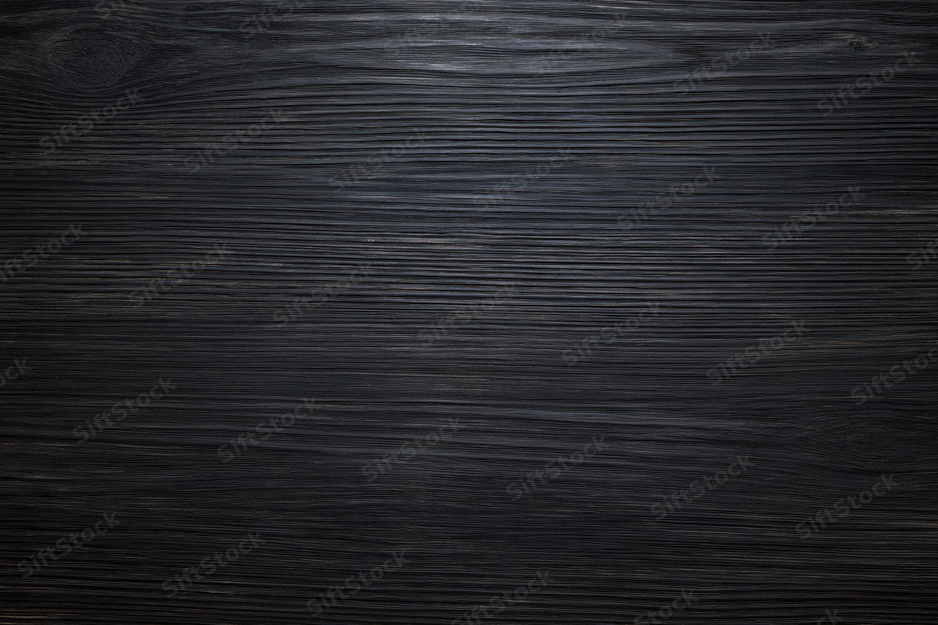 Close-up of dark ebony wood surface with visible grain pattern filling the frame