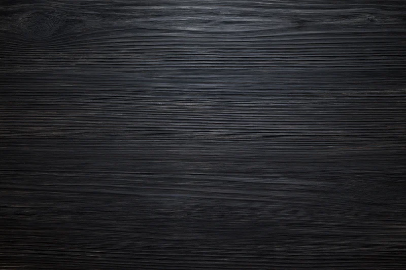 Close-up of dark ebony wood surface with visible grain pattern filling the frame