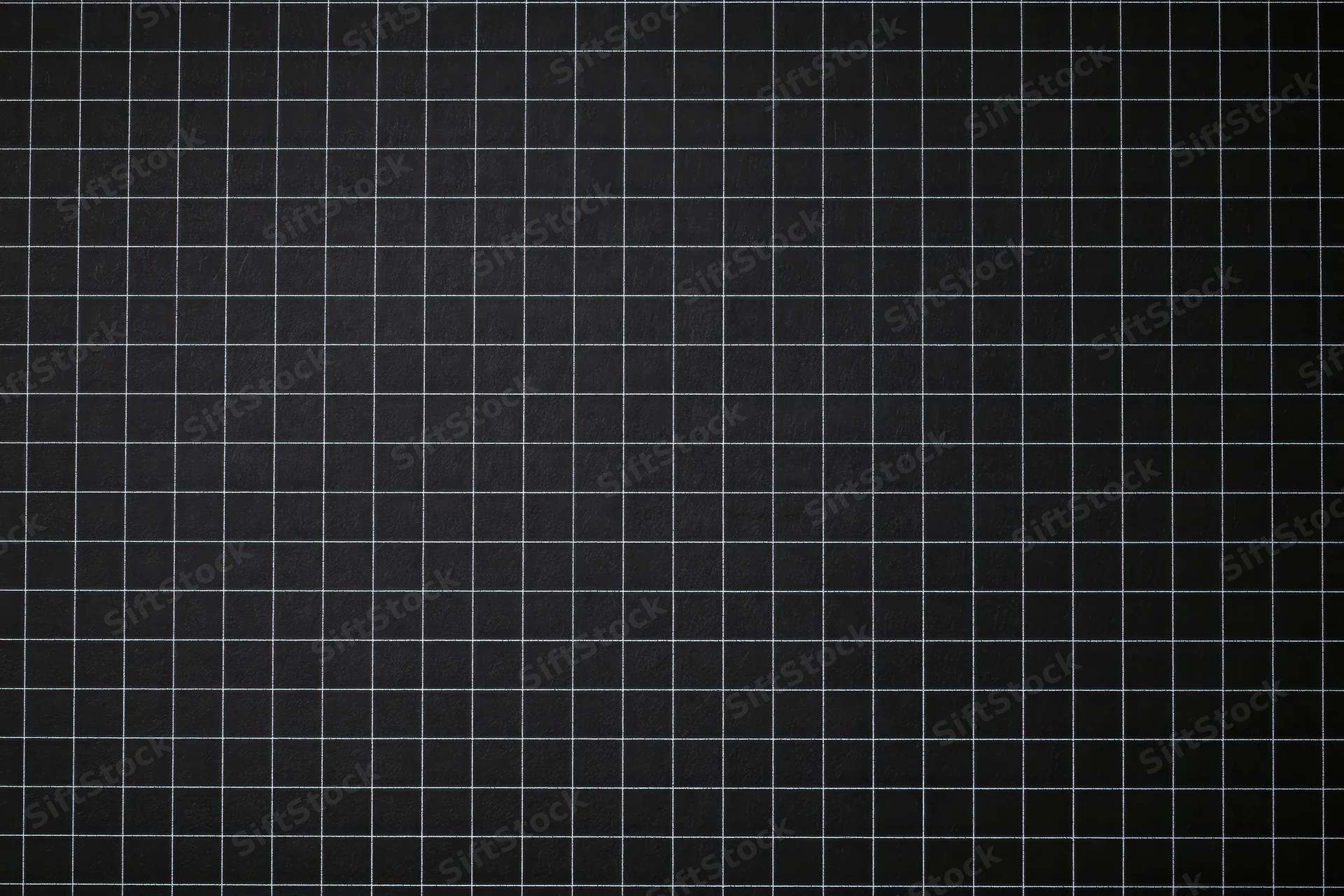 Dark matte black graph paper surface with white grid lines in flat lay view
