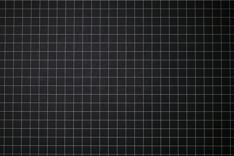 Dark matte black graph paper surface with white grid lines in flat lay view