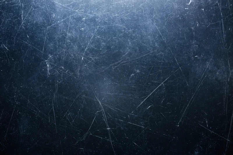 Close-up of a dark scratched matte surface with visible wear and texture