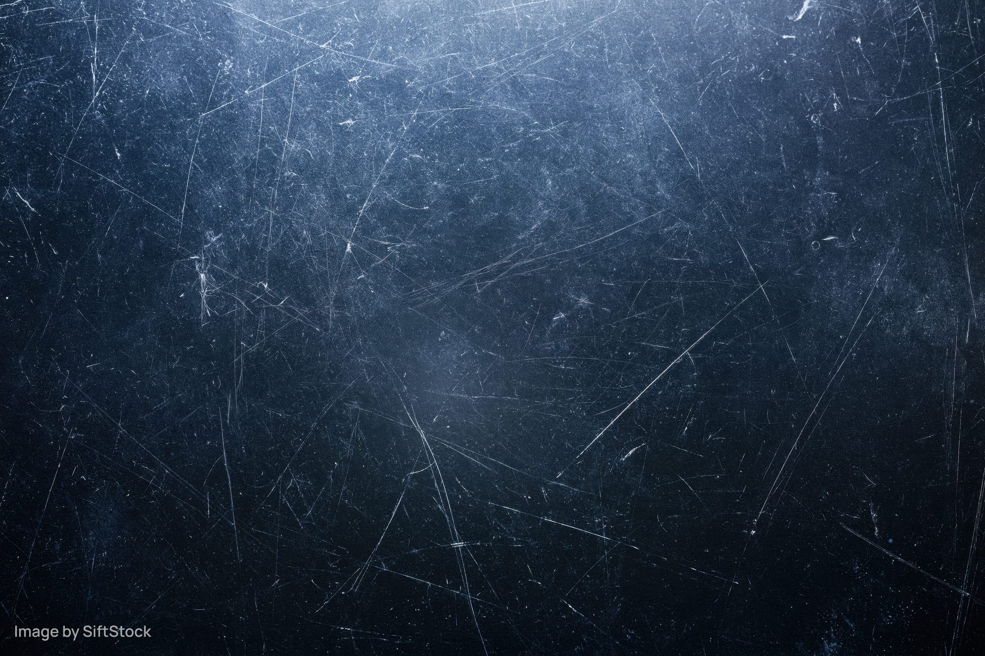 Close-up of a dark scratched matte surface with visible wear and texture