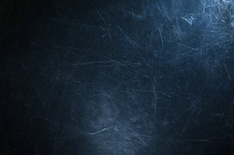 Close-up of a dark scratched matte surface with visible wear and texture