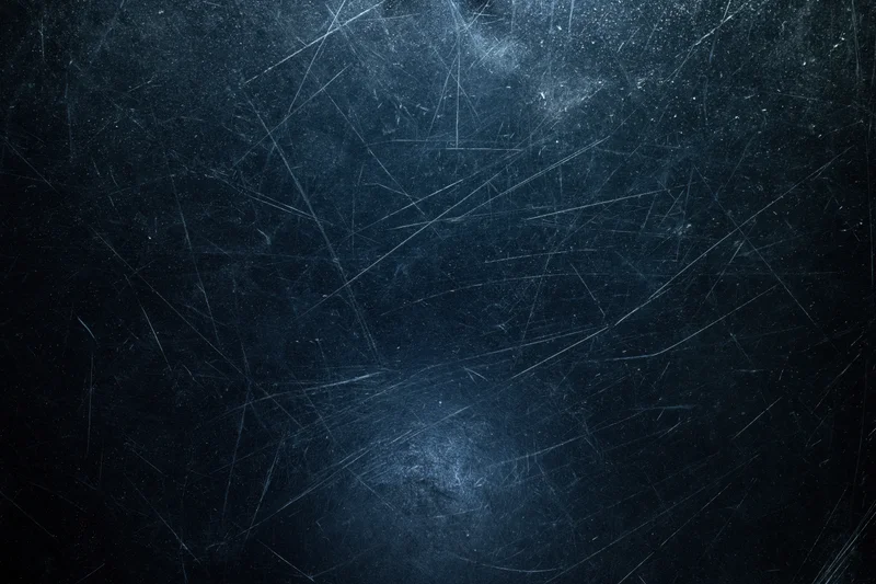 Close-up of a dark scratched matte surface with visible wear and texture