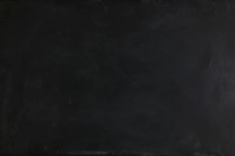 Close-up of a matte black chalkboard surface filling the frame with subtle texture and smudges