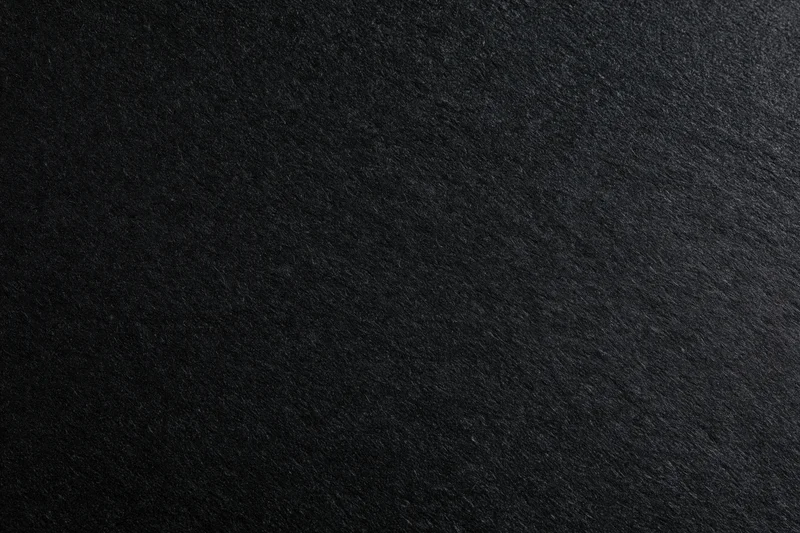 Close-up of dark charcoal black paper texture filling the frame