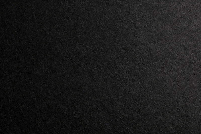 Close-up of dark charcoal black paper texture filling the frame