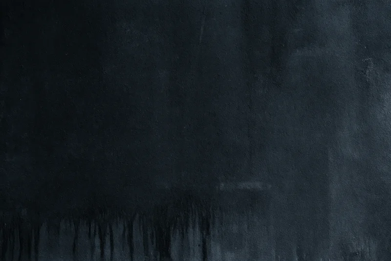 Dark matte concrete surface with rough texture and subtle stains