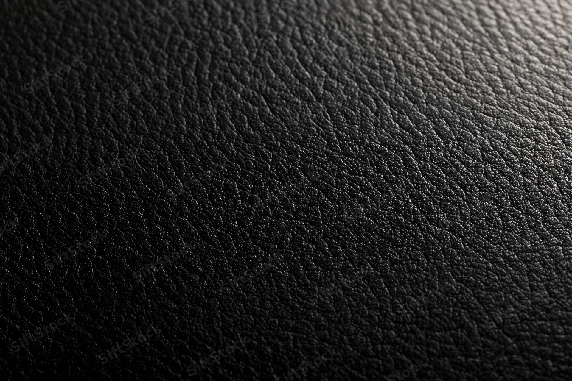 Close-up of black leather texture with visible grain and subtle lighting gradient