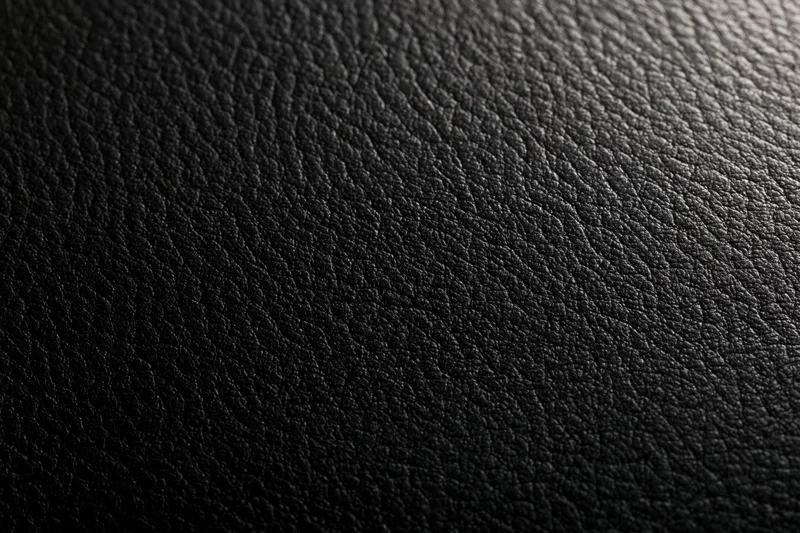 Close-up of black leather texture with visible grain and subtle lighting gradient