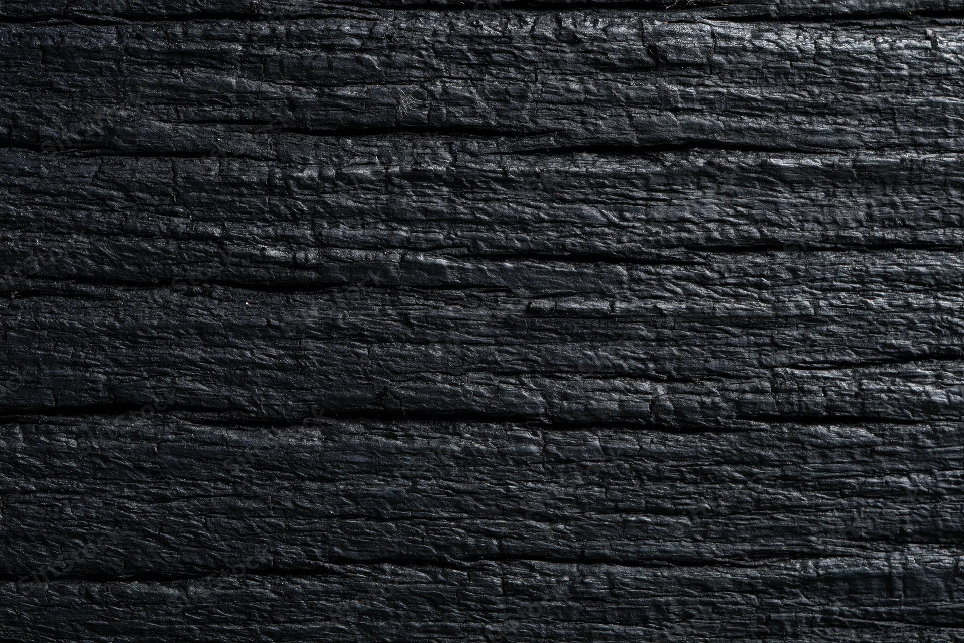 Close-up of charred black wood surface showing horizontal grain and texture