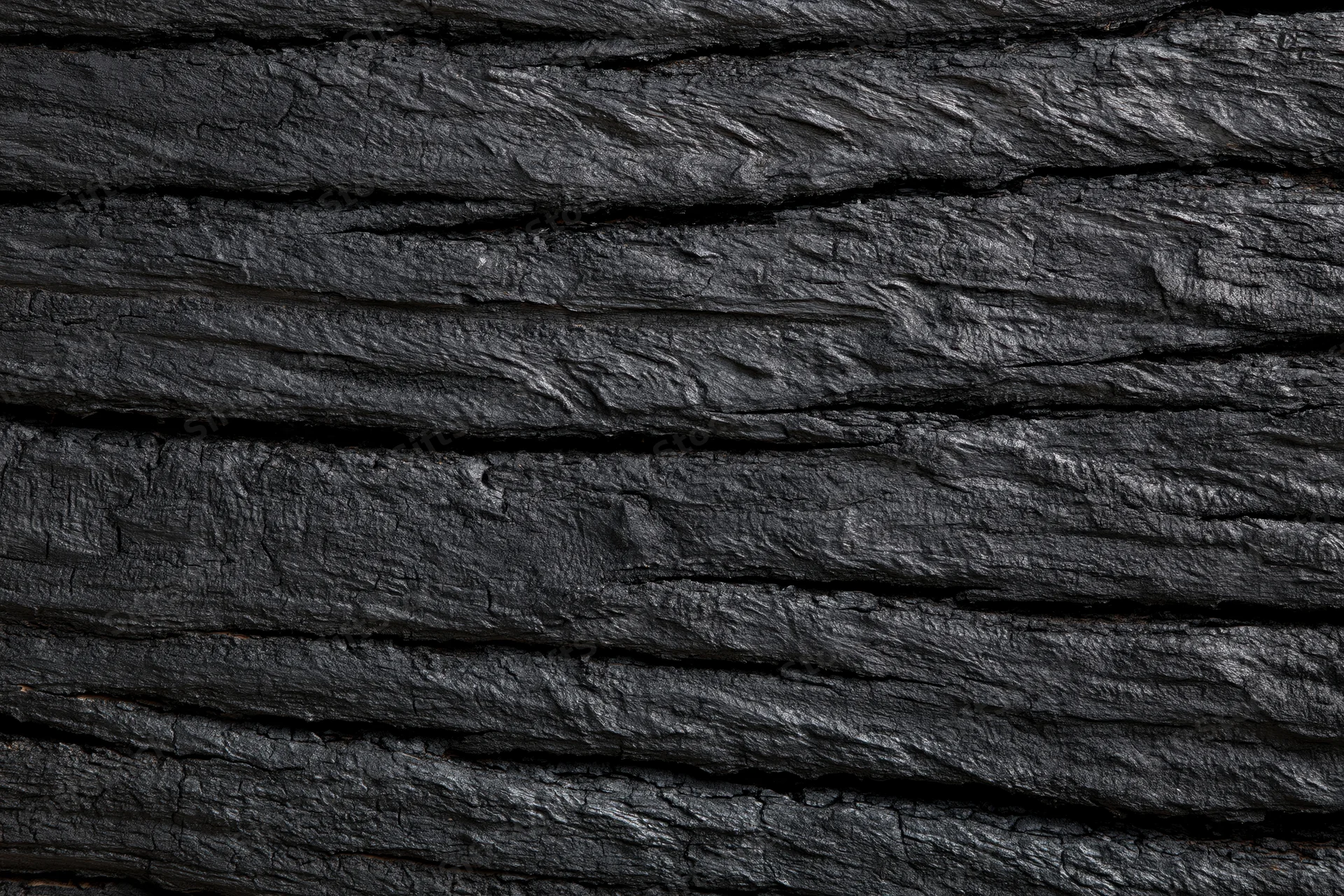 Close-up of dark charred wood surface with horizontal grain and cracked texture