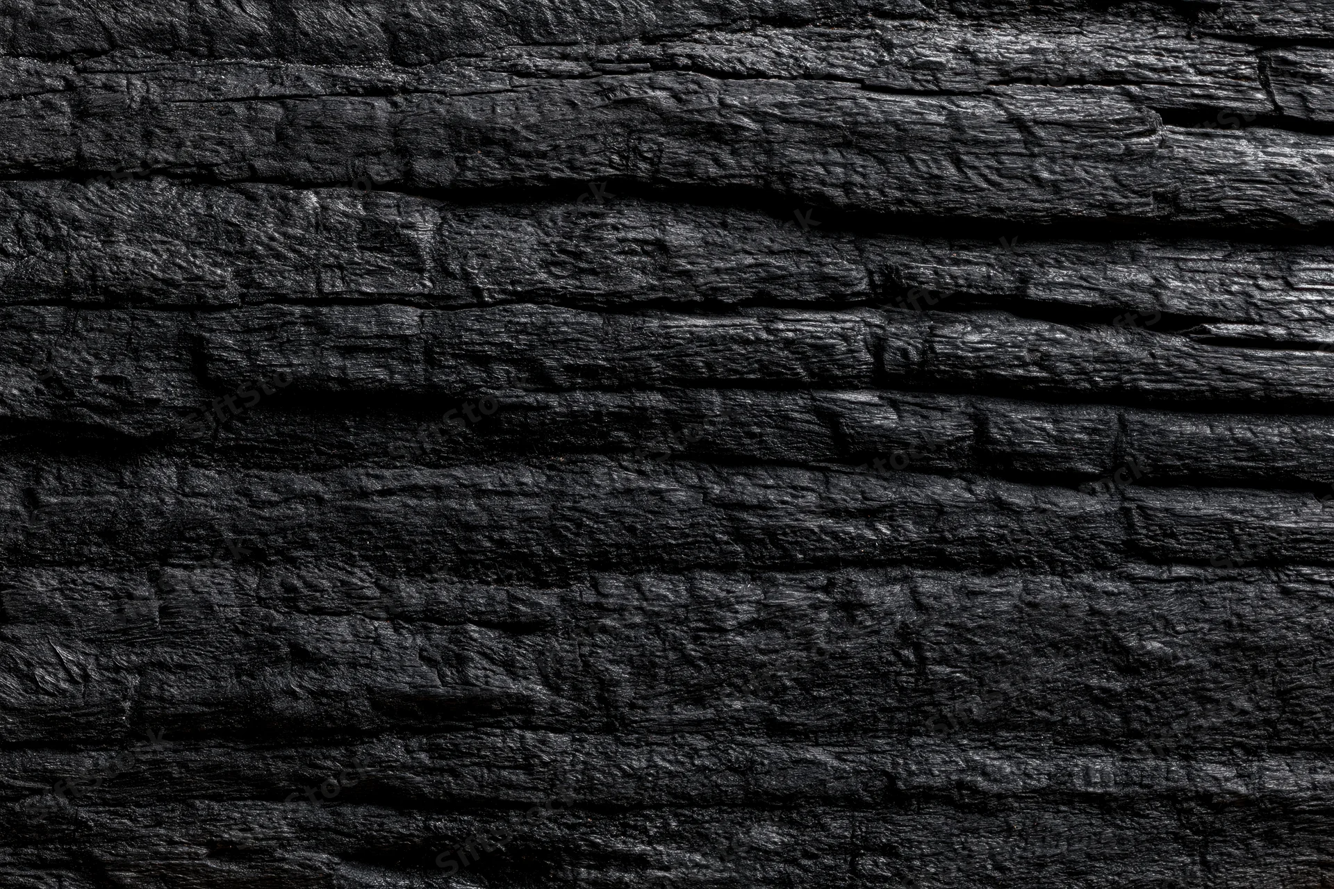 Close-up of charred wood surface showing dark textured grain and cracks