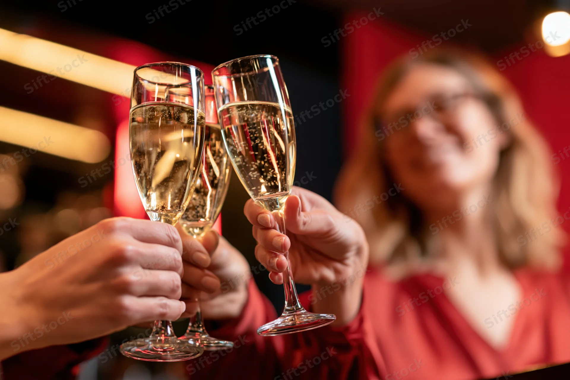 Hands clinking champagne flutes in a toast at a festive indoor gathering