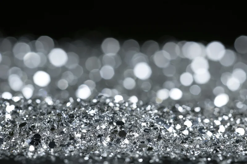 Scattered silver glitter on a flat surface with bokeh background