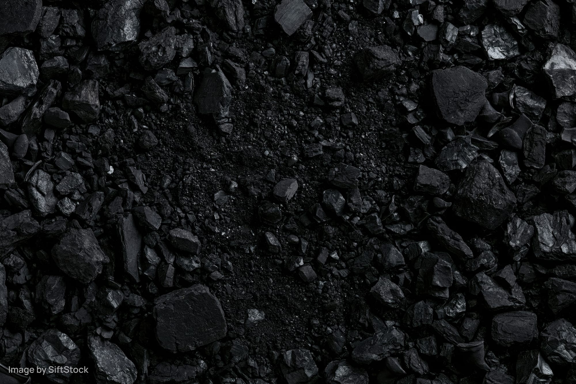 Overhead view of broken coal chunks and fragments scattered across a dark surface