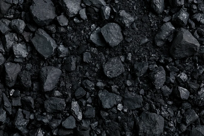 Close overhead view of broken coal chunks and fragments scattered across a dark surface