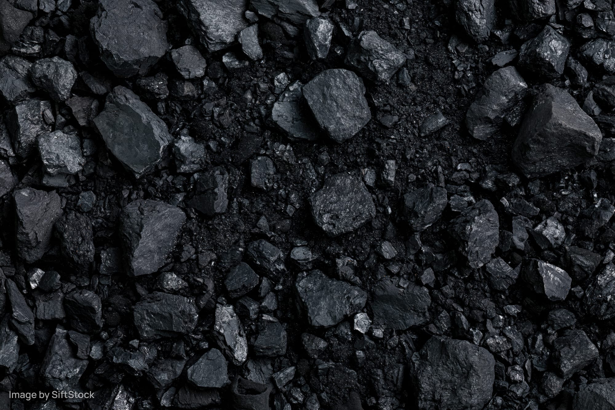 Close overhead view of broken coal chunks and fragments scattered across a dark surface