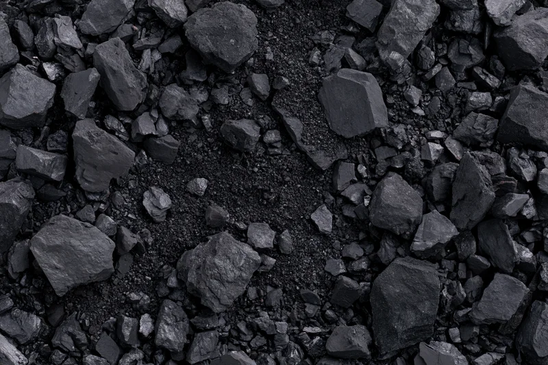 Overhead view of broken coal chunks and fragments scattered across a dark textured surface