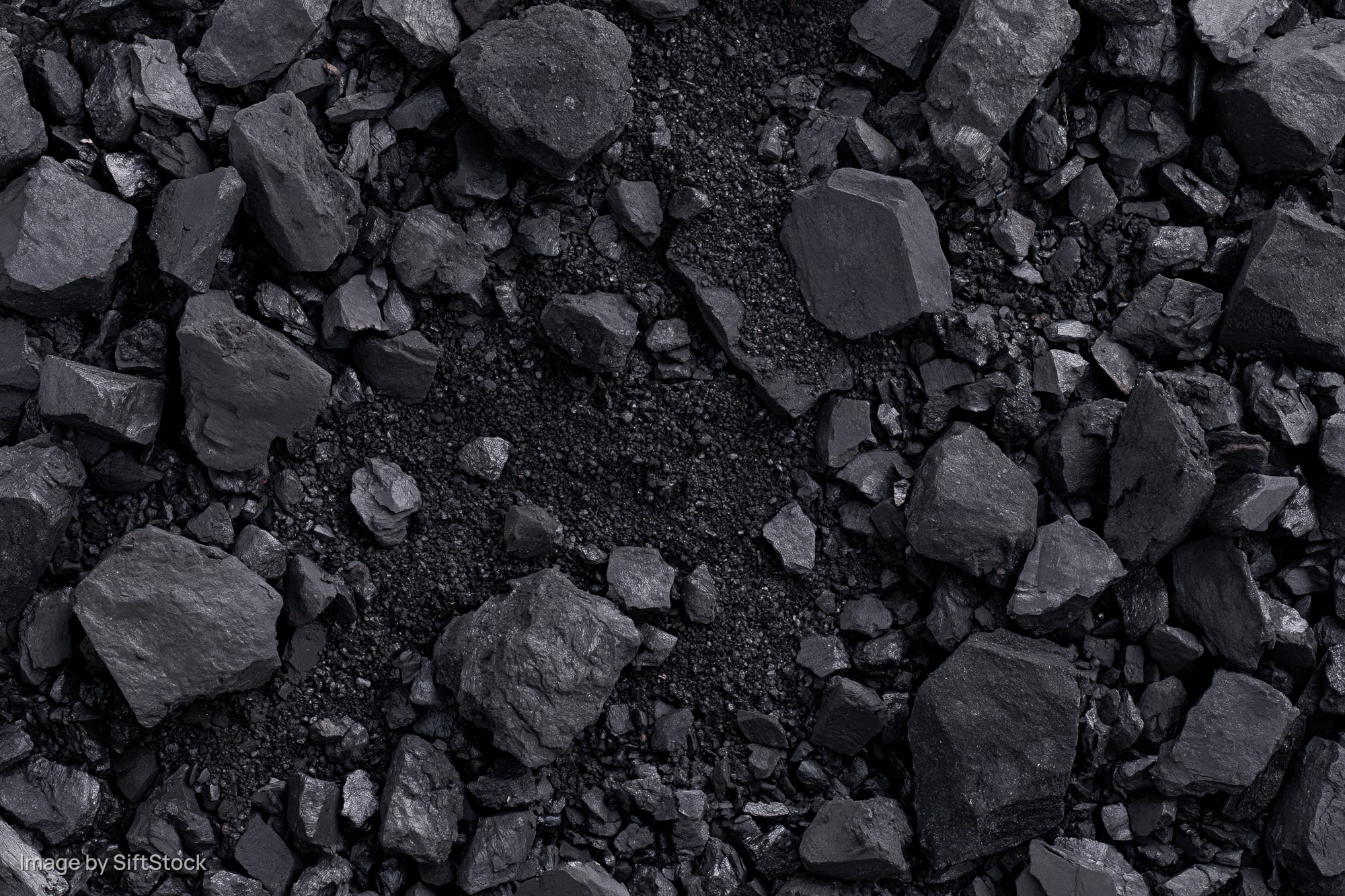 Overhead view of broken coal chunks and fragments scattered across a dark textured surface