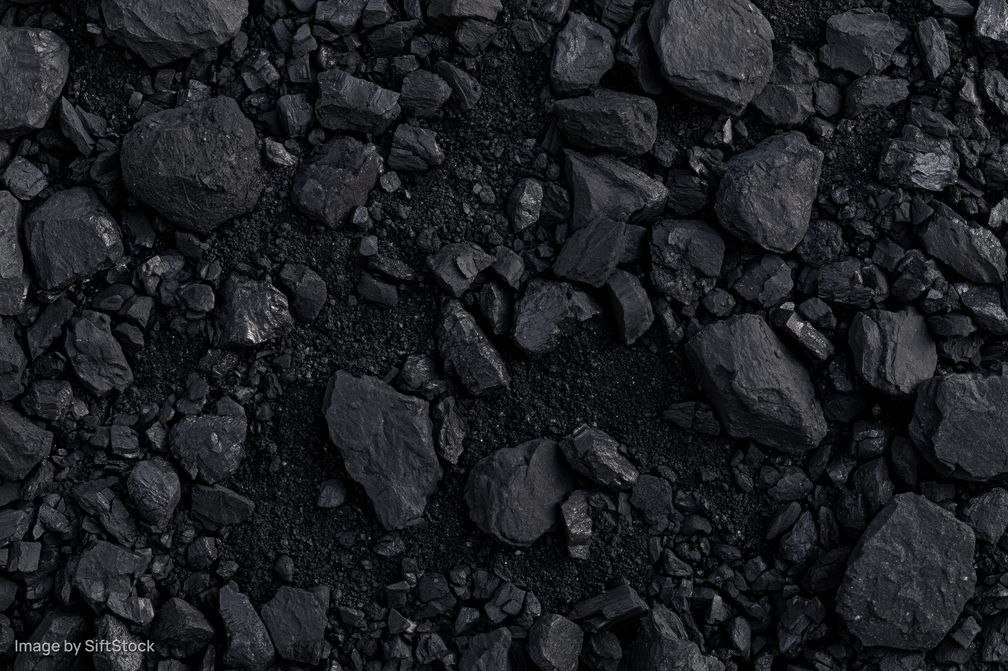 Overhead view of broken coal chunks and fragments scattered across a dark surface