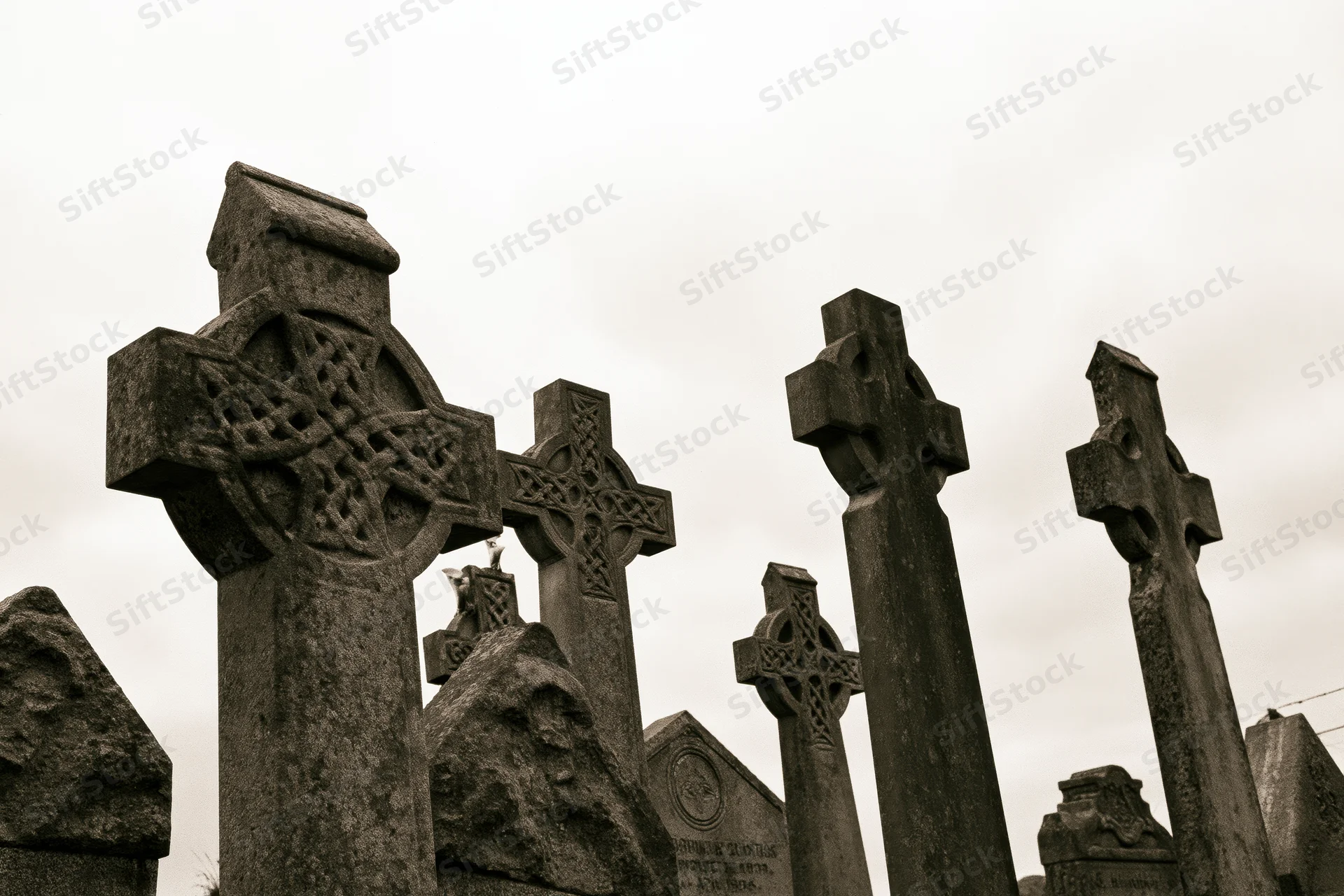Weathered celtic stone crosses standing in a cemetery under an overcast sky