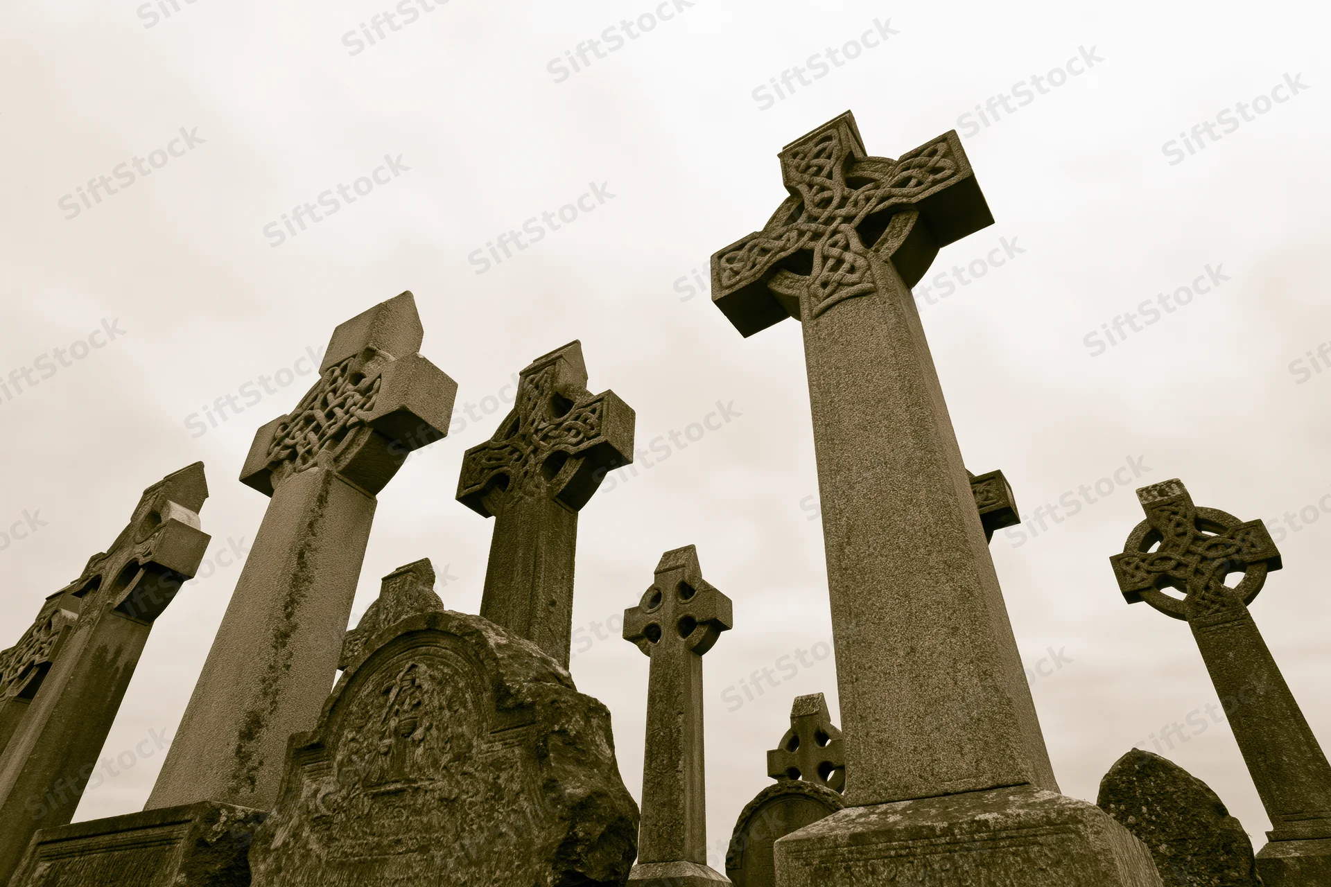 Weathered celtic stone crosses standing in a cemetery under an overcast sky