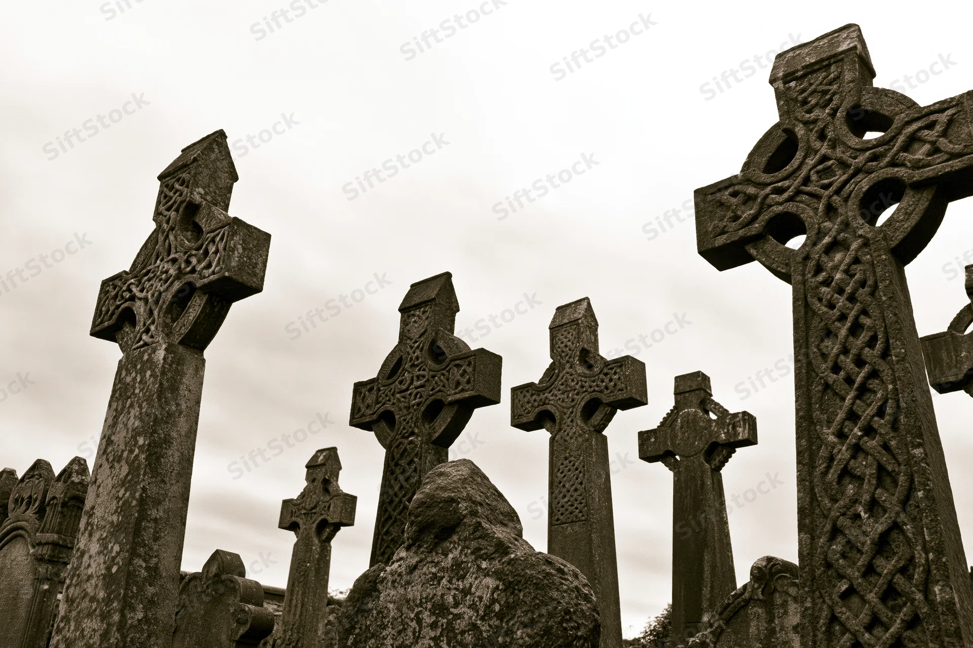 Weathered celtic stone crosses standing in a cemetery under an overcast sky