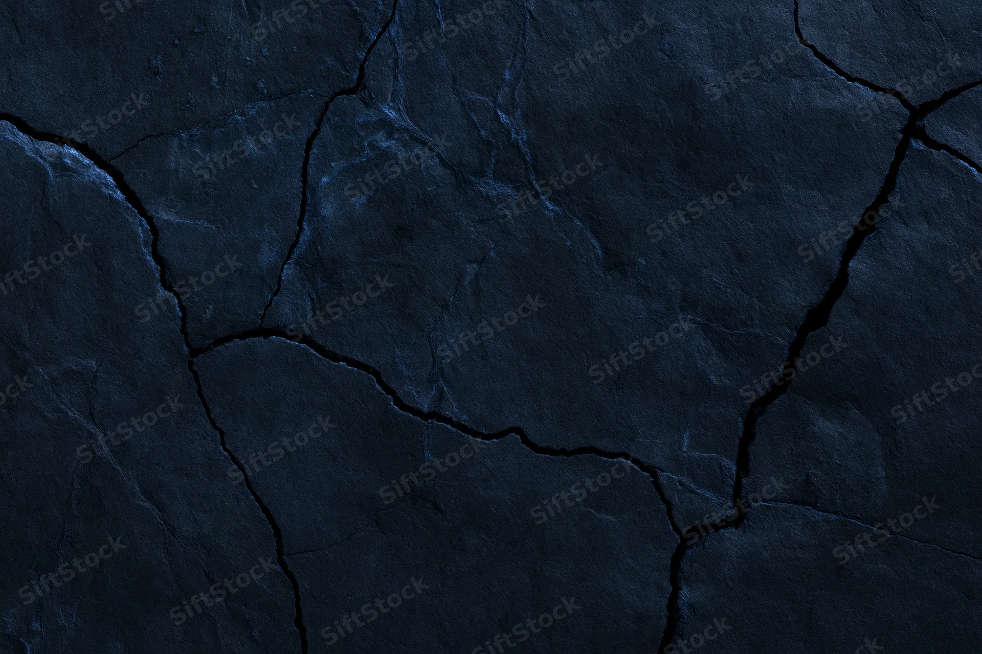 Dark cracked stone surface filling the frame with natural fissures and rugged texture
