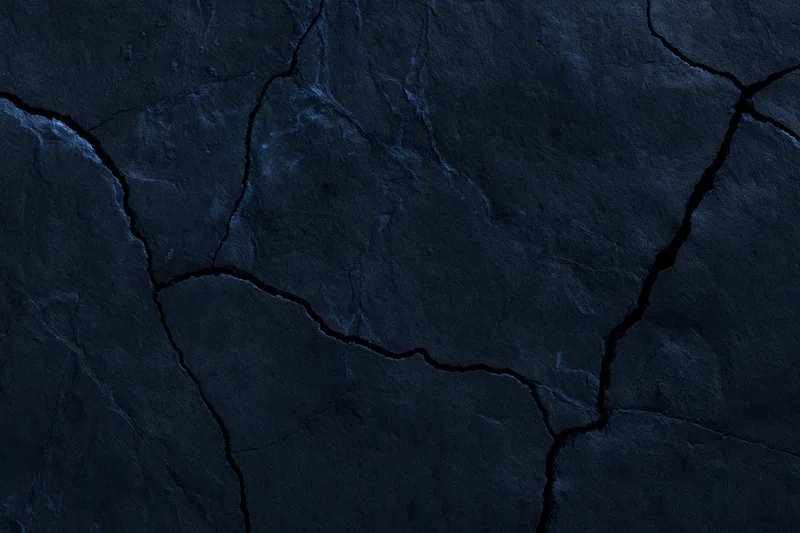 Dark cracked stone surface filling the frame with natural fissures and rugged texture