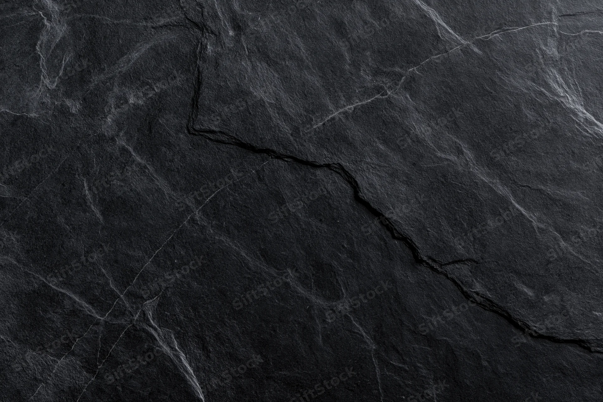 Dark slate stone surface with natural cracks and veins filling the frame