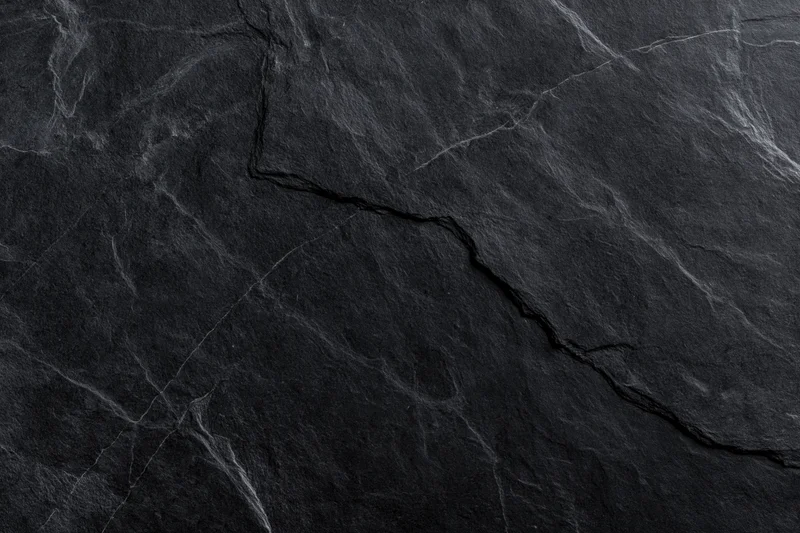 Dark slate stone surface with natural cracks and veins filling the frame