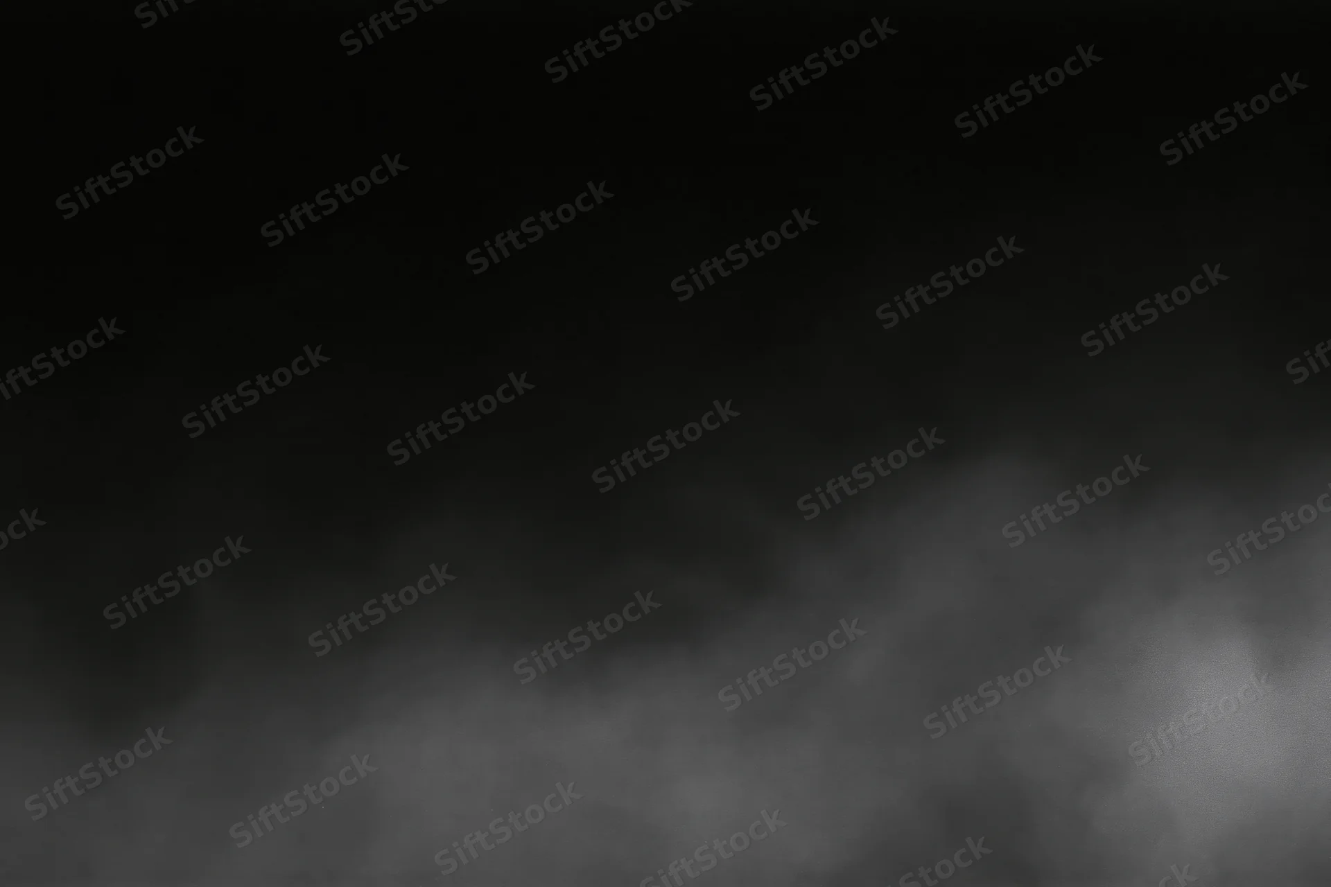 Dense fog drifting across a dark empty surface wide