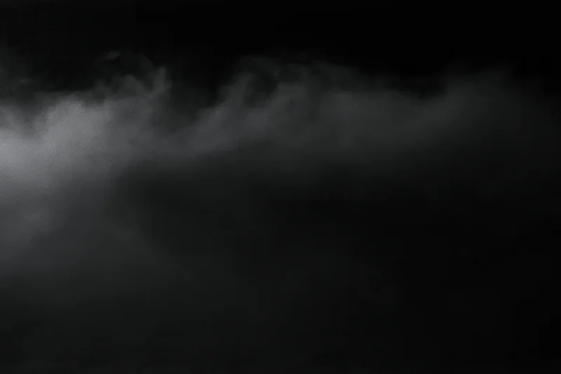Dense fog drifting across a dark empty surface at night