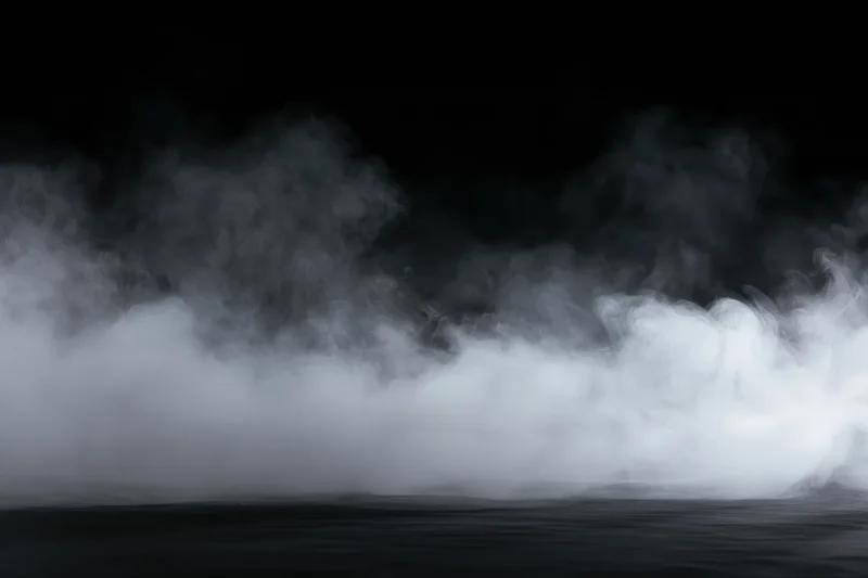 Dense white smoke drifting low across a dark surface