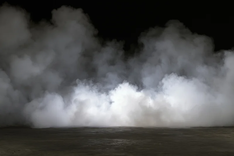 Dense white smoke rising from a dark concrete floor