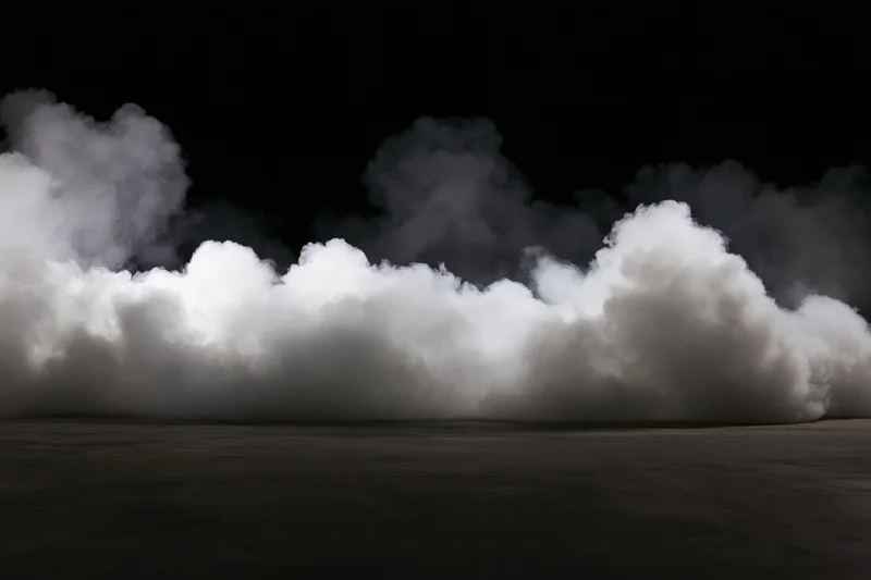 White smoke billowing upward from a dark concrete floor