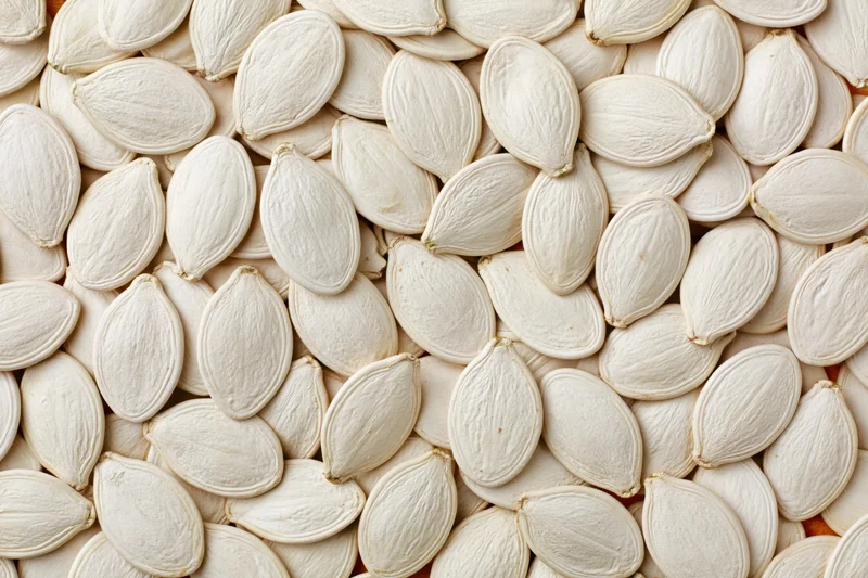 Dried white pumpkin seeds arranged in a flat lay filling the frame